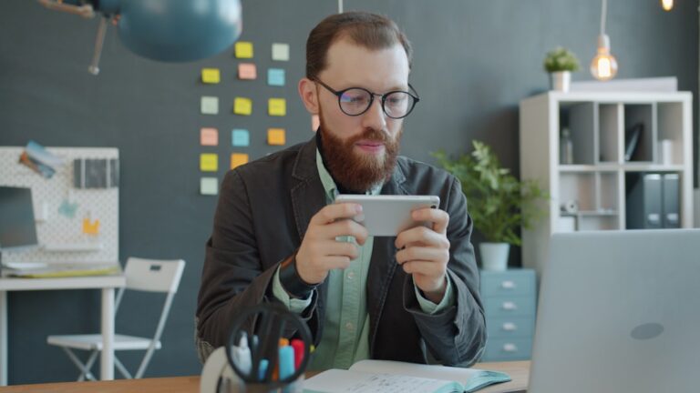 Homem Jogando Jogo No Smartphone Na Mesa Do Escritorio ATwSSCmlqag