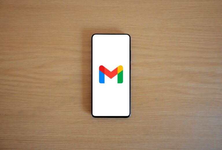 A smartphone displaying the Gmail app logo on a wooden surface, viewed from above.