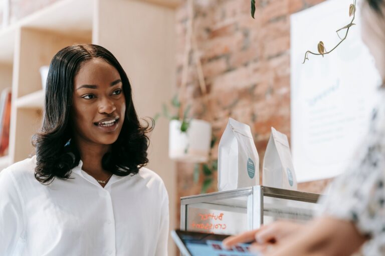 Warm interaction between a smiling barista and a customer inside a coffee shop.