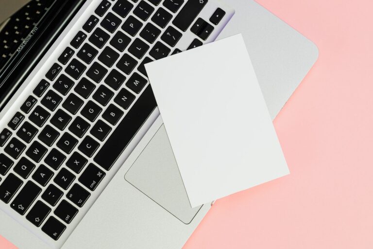 A blank card placed on a laptop keyboard with ample copy space on a pastel background.