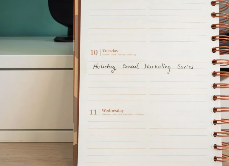 Planner open on a desk with handwritten 'Holiday Email Marketing Series' note.