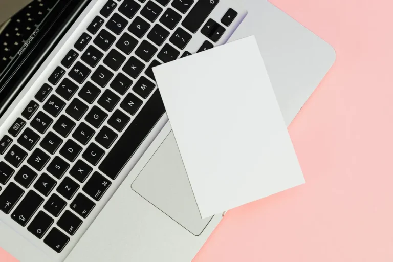 A blank card placed on a laptop keyboard with ample copy space on a pastel background.