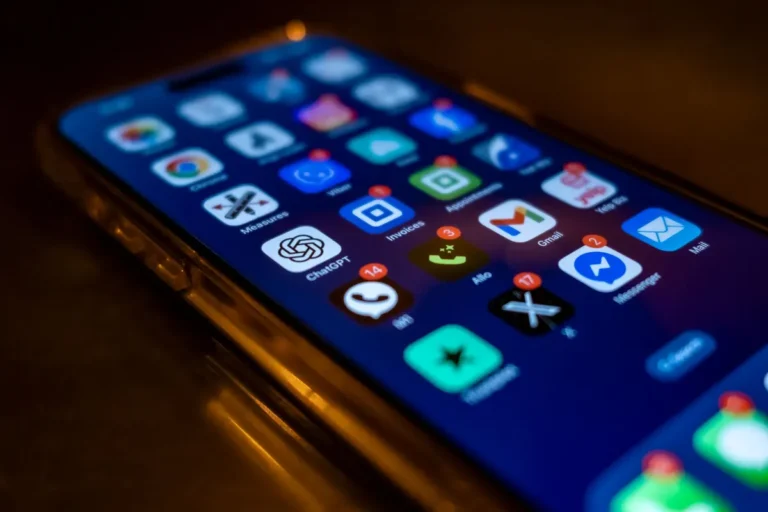 Smartphone screen showing various app icons with notification badges in low light.