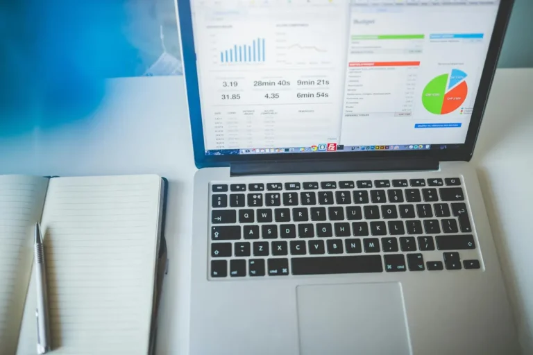Laptop displaying charts and graphs next to a notebook, ideal for business and tech themes.