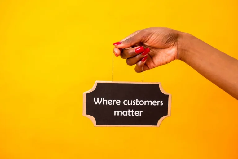 A close-up of a hand holding a sign stating Where customers matter against a bright yellow background.